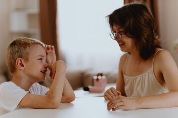Young mother helps her hard-of-hearing son with schoolwork at home. A natural, heartfelt moment of...