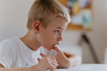 Young mother helps her hard-of-hearing son with schoolwork at home. A natural, heartfelt moment of...