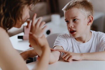 Young mother helps her hard-of-hearing son with schoolwork at home. A natural, heartfelt moment of...