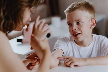 Young mother helps her hard-of-hearing son with schoolwork at home. A natural, heartfelt moment of...
