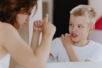 Young mother helps her hard-of-hearing son with schoolwork at home. A natural, heartfelt moment of...