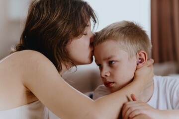 Young mother helps her hard-of-hearing son with schoolwork at home. A natural, heartfelt moment of...