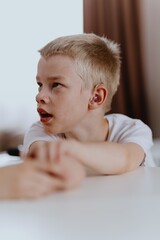 Young mother helps her hard-of-hearing son with schoolwork at home. A natural, heartfelt moment of...