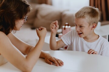 Young mother helps her hard-of-hearing son with schoolwork at home. A natural, heartfelt moment of...