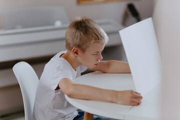 Young mother helps her hard-of-hearing son with schoolwork at home. A natural, heartfelt moment of...