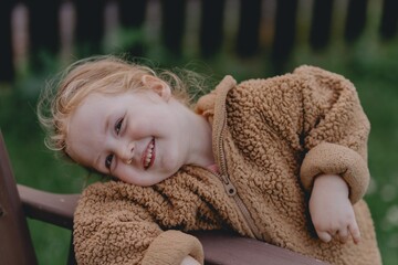 Beautiful 3-year-old girl playing on a neighborhood playground swinging, running on the grass, and enjoying fresh air. A joyful, natural moment full of real emotions and unaltered beauty