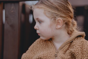 Beautiful 3-year-old girl playing on a neighborhood playground swinging, running on the grass, and enjoying fresh air. A joyful, natural moment full of real emotions and unaltered beauty