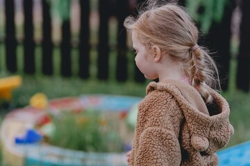 Beautiful 3-year-old girl playing on a neighborhood playground swinging, running on the grass, and enjoying fresh air. A joyful, natural moment full of real emotions and unaltered beauty