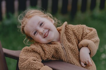 Beautiful 3-year-old girl playing on a neighborhood playground swinging, running on the grass, and enjoying fresh air. A joyful, natural moment full of real emotions and unaltered beauty