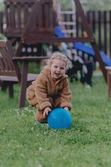 Beautiful 3-year-old girl playing on a neighborhood playground swinging, running on the grass, and enjoying fresh air. A joyful, natural moment full of real emotions and unaltered beauty