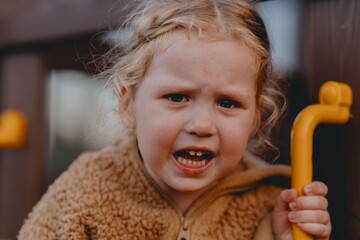 Beautiful and active 3-year-old girl plays on a neighborhood playground but becomes upset and starts crying. A raw, unaltered moment capturing real childhood emotions in a natural outdoor