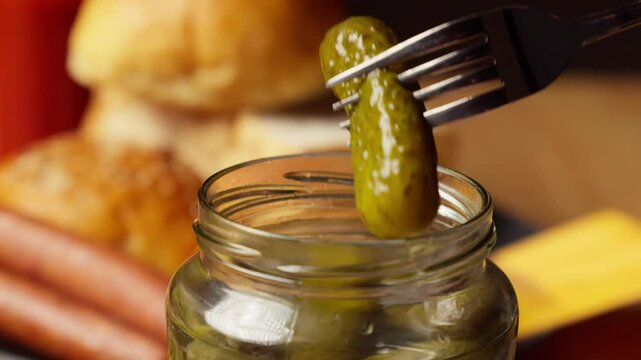 a person is grabbing a cucumber pickle from the jar with a fork