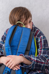 Child resting with a blue backpack while sitting indoors in a casual and comforting setting during a quiet afternoon