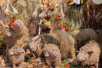 Artistic display of straw animals adorned with flowers in a vibrant festival setting