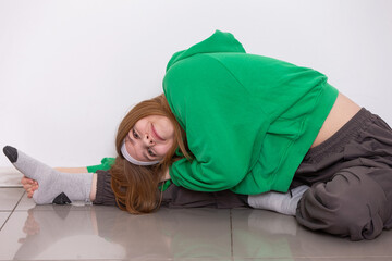 Teen girl in green sweatshirt demonstrates impressive flexibility while stretching in a bright room during a yoga session