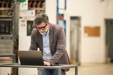 Business Professional Working on Laptop in a Modern Industrial Workspace