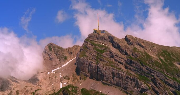Mountain summit view with observation tower surrounded by clouds in a clear blue sky
