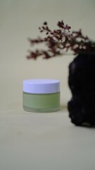 small glass jar with white cap containing light green liquid substance rests against piece of weathered wood adding natural element creating balanced aesthetic to the composition. 