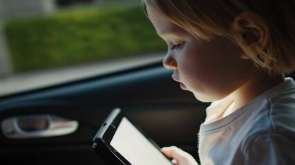 Young female passenger engaging with handheld gaming device during road trip, enjoying digital entertainment while traveling through scenic landscape inside moving vehicle