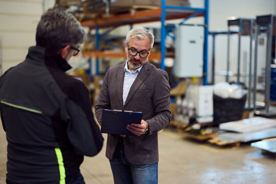 Manager Discussing Warehouse Operations with Worker in Industrial Setting