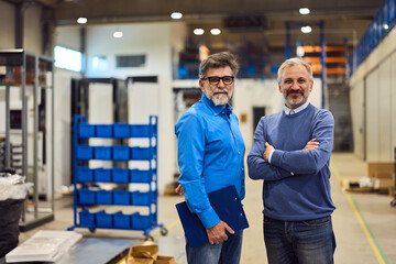 Fototapeta premium Two Professionals Smiling Confidently in a Modern Industrial Warehouse Environment