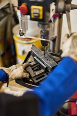 Worker Operating Drill Press on Metal Piece in Workshop