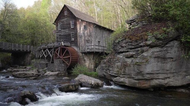 Babcock State Park showcases vibrant spring foliage along a rushing creek, featuring a historic grist mill nestled amid lush forest and serene landscapes.
