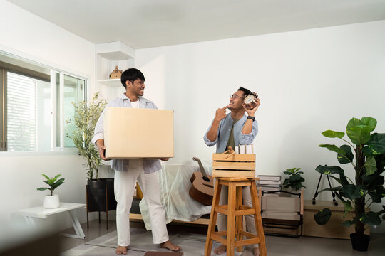 Gay couple enjoying unpacking boxes and decorating their new home
