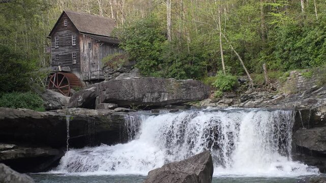Babcock State Park showcases vibrant spring foliage along a rushing creek, featuring a historic grist mill nestled amid lush forest and serene landscapes.