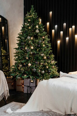 Bedroom interior decorated for Christmas holidays. Home interior with a Christmas tree on a dark wall background.