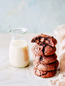 Stack of chocolate cookies with chocolate chips and a glass of milk