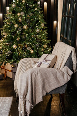 The interior of the bedroom is decorated for the Christmas holidays. Home interior with Christmas tree, armchair and gifts.