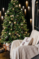 The interior of the bedroom is decorated for the Christmas holidays. Home interior with Christmas tree, armchair and gifts.