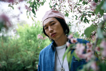 Stylish young man enjoying a spring day in a park surrounded by blooming flowers