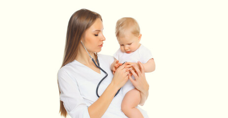 Young woman doctor holding baby and listens to his heart standing on white background