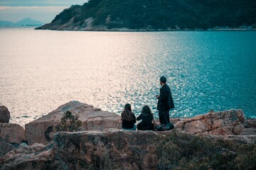 Young adults overlooking ocean from rocky cliffs.
