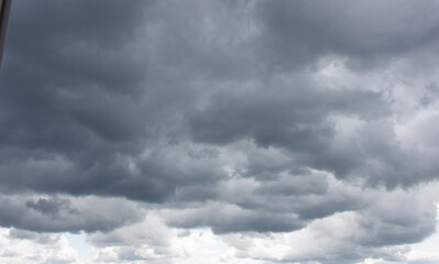 Obraz premium Dark storm clouds with rain. Storm clouds of various soft shapes in the sky. Changeable weather. Fluffy clouds above the sky