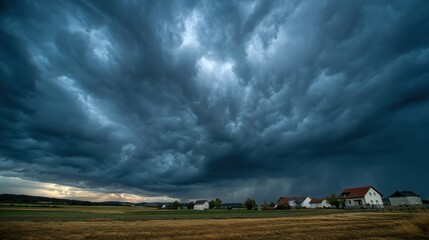 Fototapeta premium Dramatic stormy sky over rural landscape with dark clouds and houses