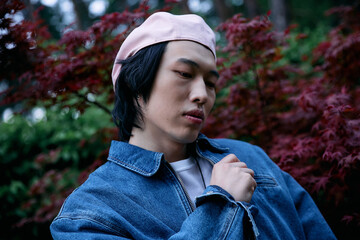 Young man showcases denim fashion in a serene park under soft natural light