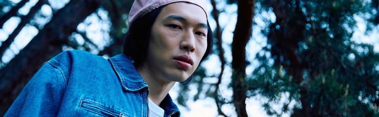 Stylish young man enjoys a serene moment in a park with denim fashion