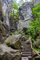 Rocky hiking trail with stone stairs winding through sandstone formations in Saxon Switzerland National Park near Rathen, Germany – a scenic route for outdoor enthusiasts.
