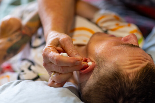 Middle aged woman cleaning ears of son with disability with cotton tips