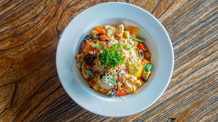 Top view of pasta primavera in a white plate on wooden table