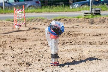 covered water pipeline valve at construction site surrounded by sand and roadwork elements prepared...