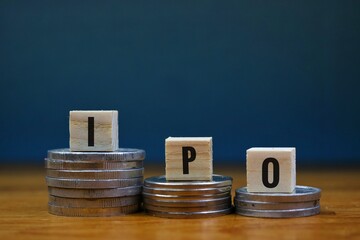 stock market and investment concept. ipo writing on wooden block and stack of coins isolated on navy blue background