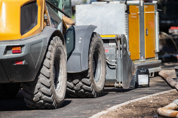 heavy construction vehicle with large tires and industrial equipment parked on asphalt road at construction site with machinery and tools for urban infrastructure © K