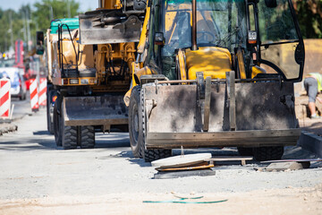 Yellow construction machinery on roadwork site with bulldozer and heavy equipment preparing ground for new pavement showing urban development and infrastructure repair