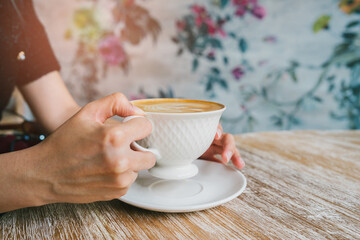 Coffee in cafe. Elegant Ceramic Cup of Coffee Being Held by Woman with Beautiful Floral Background in Cozy Cafe Setting