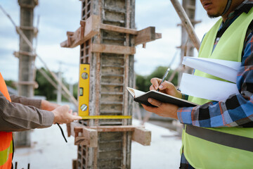 A construction worker inspects a concrete pillar using a level, ensuring precision and quality...