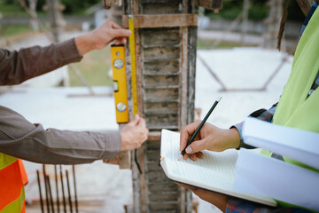 A construction worker inspects a concrete pillar using a level, ensuring precision and quality...